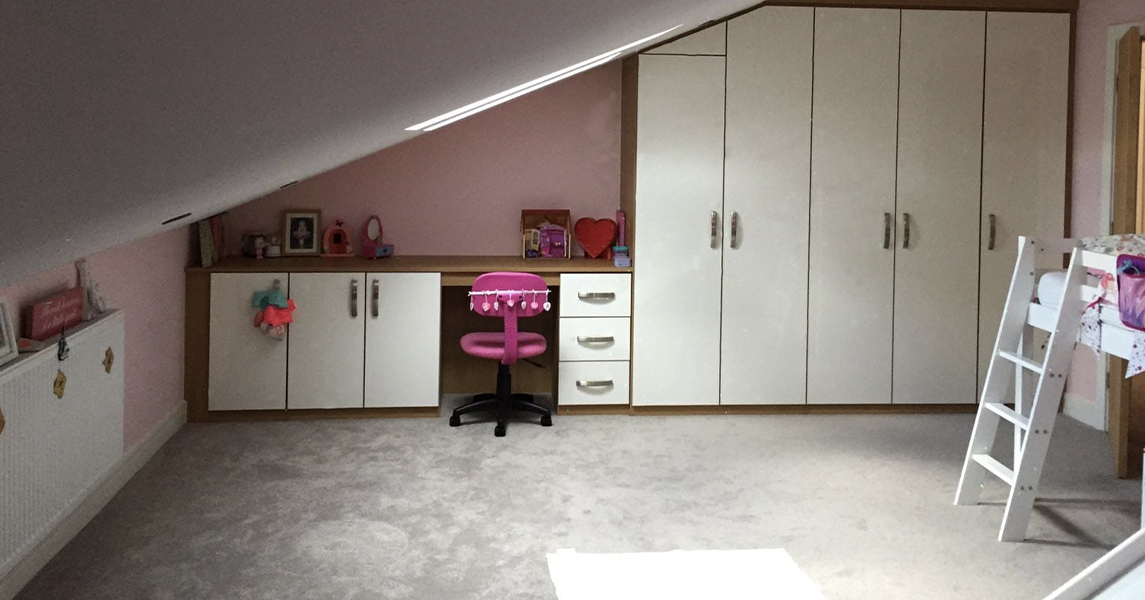 Fitted wardrobes with a matching fitted desk and drawers in a cream and oak finish.