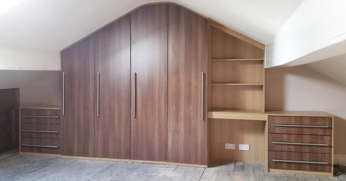 Fitted wardrobes with a matching desk and drawers in a dark walnut finish.