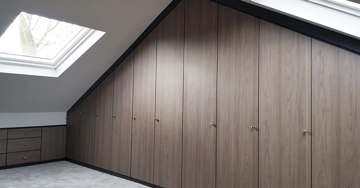 Dark Walnut fitted wardrobes and chest of drawers in an attic/loft space.