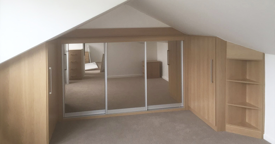 Fitted wardrobes with a matching desk and drawers in a dark walnut finish.