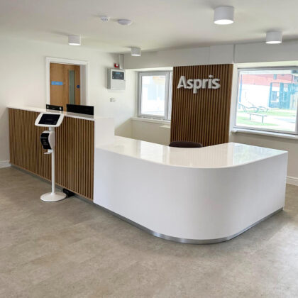 Modern reception desk with solid surface countertop and vertical wooden slat panels.