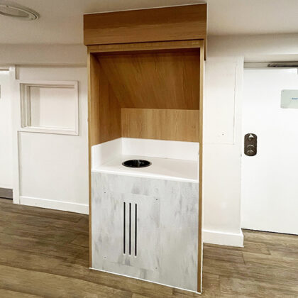 Anti-ligature tea station with sloped top and enclosed base in a secure facility corridor.